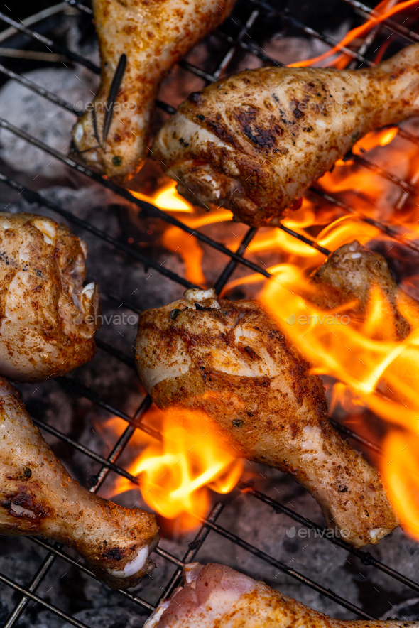 BBQ Chicken Drumsticks Over Fire Flames on Grill Stock Photo by merc67